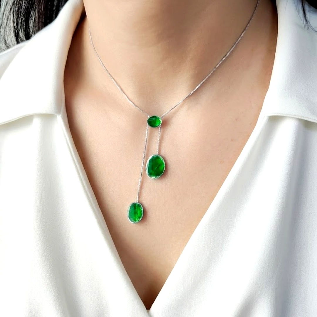 Silver necklace with green gemstones on a white fabric background. Palestine handmade jewelry owned