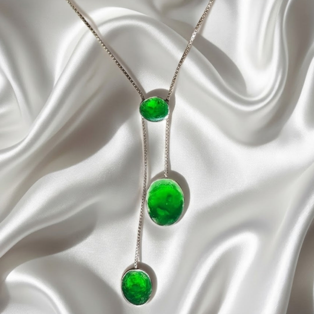 Silver necklace with green gemstones on a white fabric background. Palestine handmade jewelry owned brand