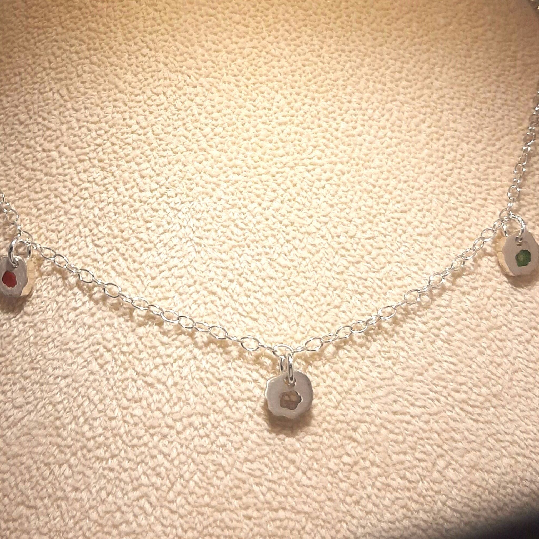 Gold plated chain necklace with three hammered disc charms set with black stones, worn on model 